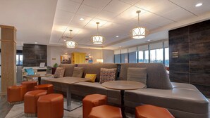 Een moderne zithoek met een bank, poefs en een ronde tafel.