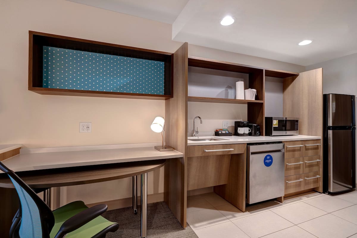 Een moderne keuken met houten kastjes, een ingebouwde magnetron, een koelkast en een aanrecht met een spoelbak.