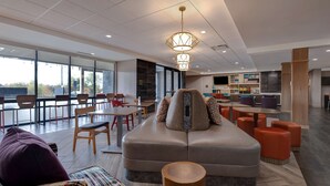 Een ruime, moderne zithoek met comfortabele stoelen, een centrale salontafel en een groot raam met uitzicht op de omgeving.