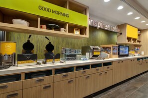 Un área de cocina moderna con una estación de café, un expositor para productos de desayuno y un letrero que dice 'inspired table'.