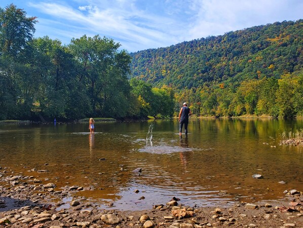 A riverbank with rocks and a person standing in the water.