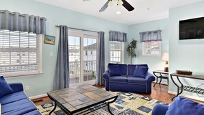 A living room with a blue sofa, a coffee table, and a TV.