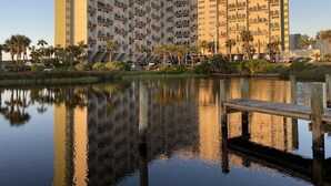 Ein mehrstöckiges Hotel mit Balkonen, Blick auf das Wasser und einem Steg.