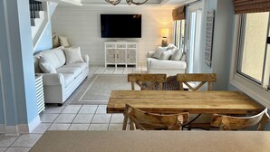 Ein modernes Wohnzimmer mit einem großen Fernseher, einem Holzesstisch und zwei Sofas.