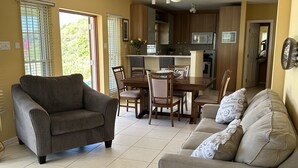 Una sala con un sofá gris, un sofá beige y una mesa de comedor con sillas.