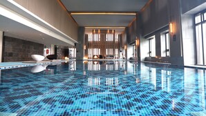 A modern indoor swimming pool with a blue mosaic floor, a reception area with seating, and large windows allowing natural light. - Wuhan Marriott Hotel Optics Valley (Wuhan)