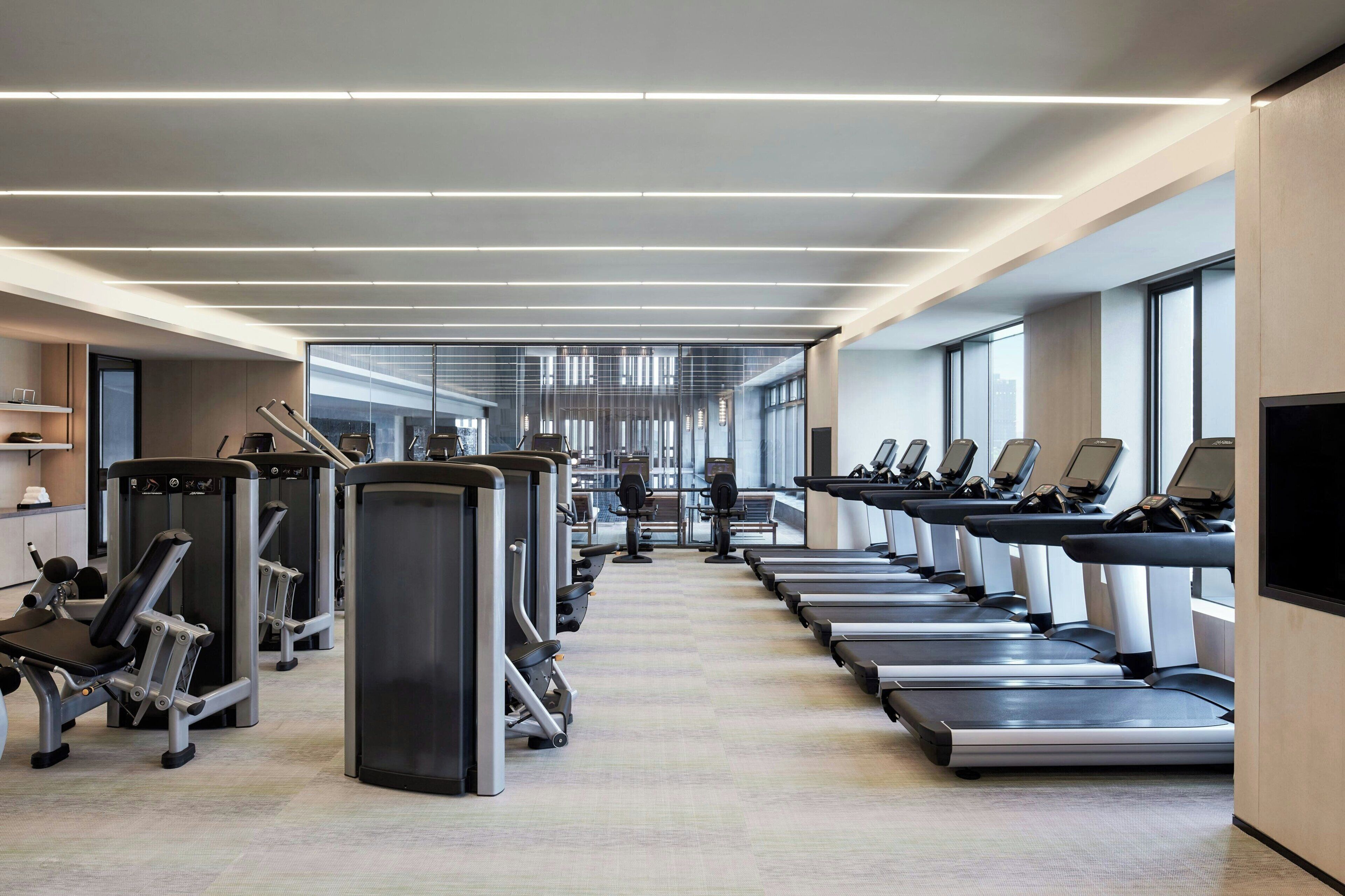 Un gimnasio moderno con cintas de correr, máquinas de pesas y un amplio espacio.