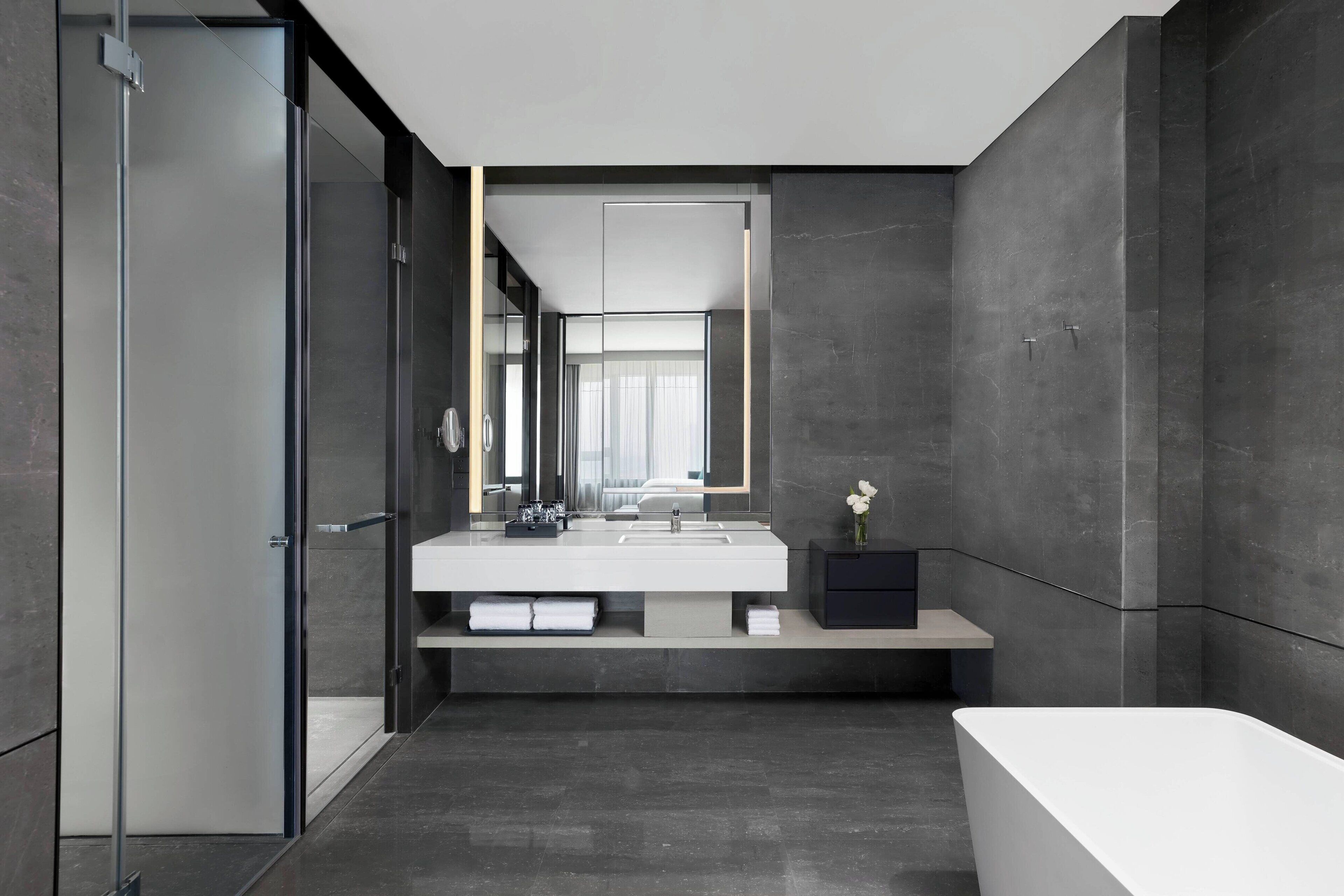 Un baño moderno con un espejo grande, un lavabo blanco y una bañera.