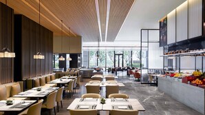 A modern restaurant with a long dining area, high ceilings, and a view of the outdoors. - Wuhan Marriott Hotel Optics Valley (Wuhan)