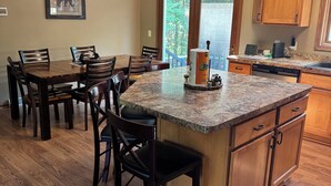 Une cuisine avec des meubles en bois, un plan de travail en granit et un coin repas comprenant des chaises et une table.
