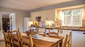 Une cuisine moderne avec des meubles en bois, une table à manger avec des chaises et un lave-vaisselle encastré.