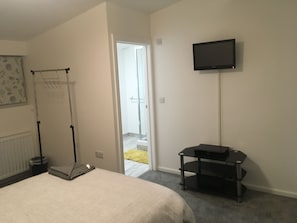 Ein Schlafzimmer mit Bett, einem an der Wand befestigten Fernseher und einer Tür, die auf einen Balkon führt.
