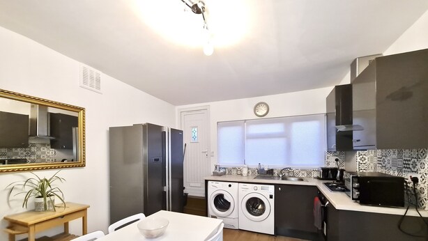 Una cocina compacta equipada con refrigerador, lavadora, microondas y un comedor con mesa y sillas.