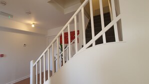 Una escalera con barandillas blancas y una pared roja en la parte superior.