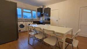Una cocina compacta con una mesa de comedor y sillas, lavadora y refrigerador.
