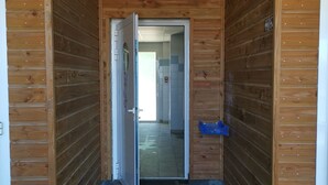 Una baita in legno con un corridoio stretto che conduce a una stanza con pavimento piastrellato.