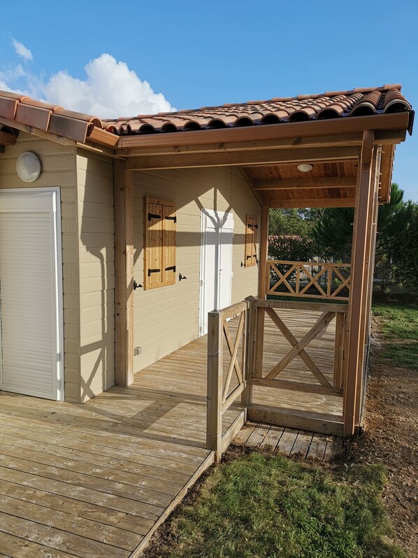 A wooden deck leading to a building with a tiled roof and a covered porch area.