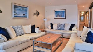 A modern living room with two sofas, a coffee table, and artwork on the walls. - Harbourside Apartment (St Austell)