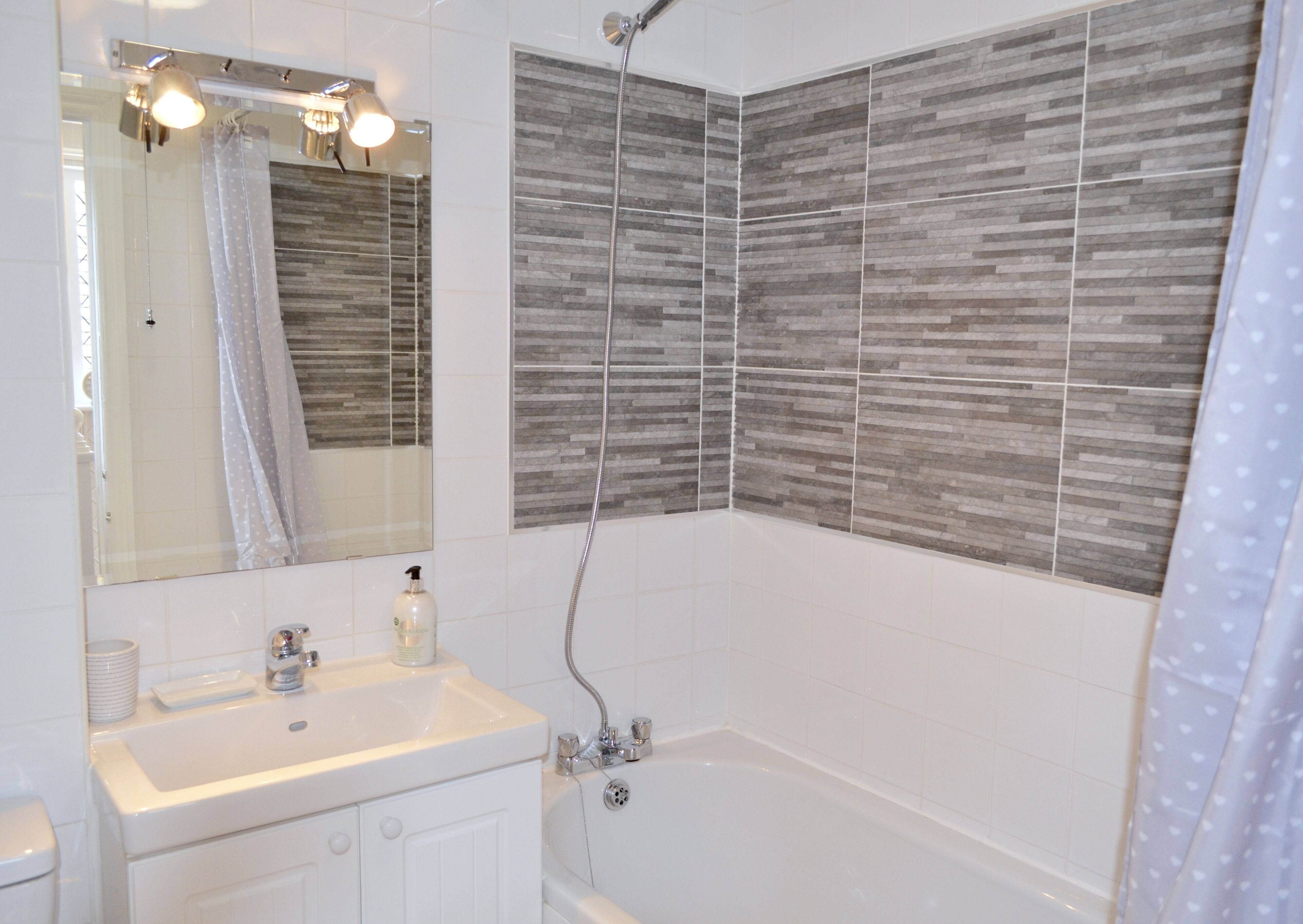 A modern bathroom with a white sink, mirror, and shower.