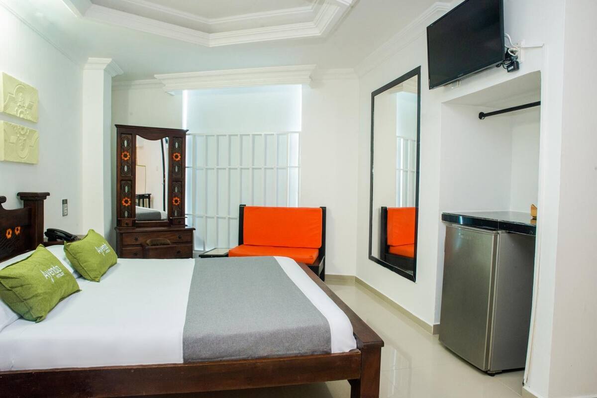 Une chambre d’hôtel équipée d’un lit, d’un bureau, d’une chaise, d’une télévision et d’un réfrigérateur.