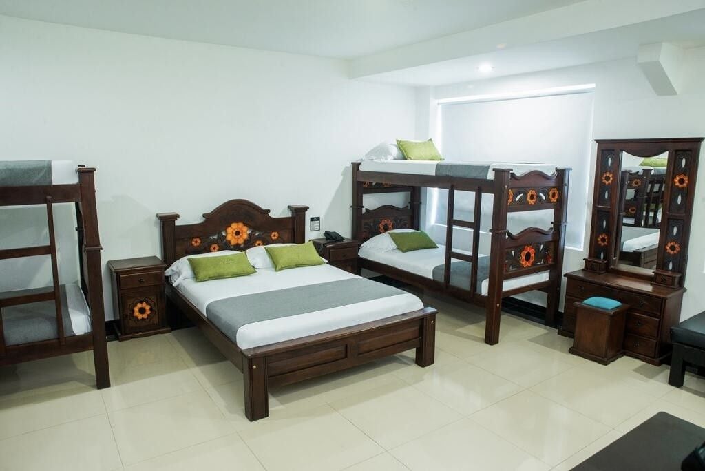 A room with bunk beds, a bedside table, a dresser, and a mirror.