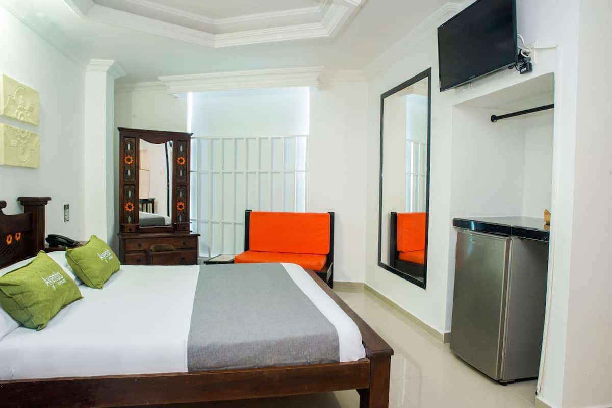 Une chambre d’hôtel équipée d’un lit, d’un bureau, d’une chaise, d’une télévision et d’un réfrigérateur.