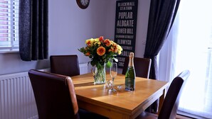A dining table with a vase of flowers, a bottle of champagne, and wine glasses. - River Mist (Telford)