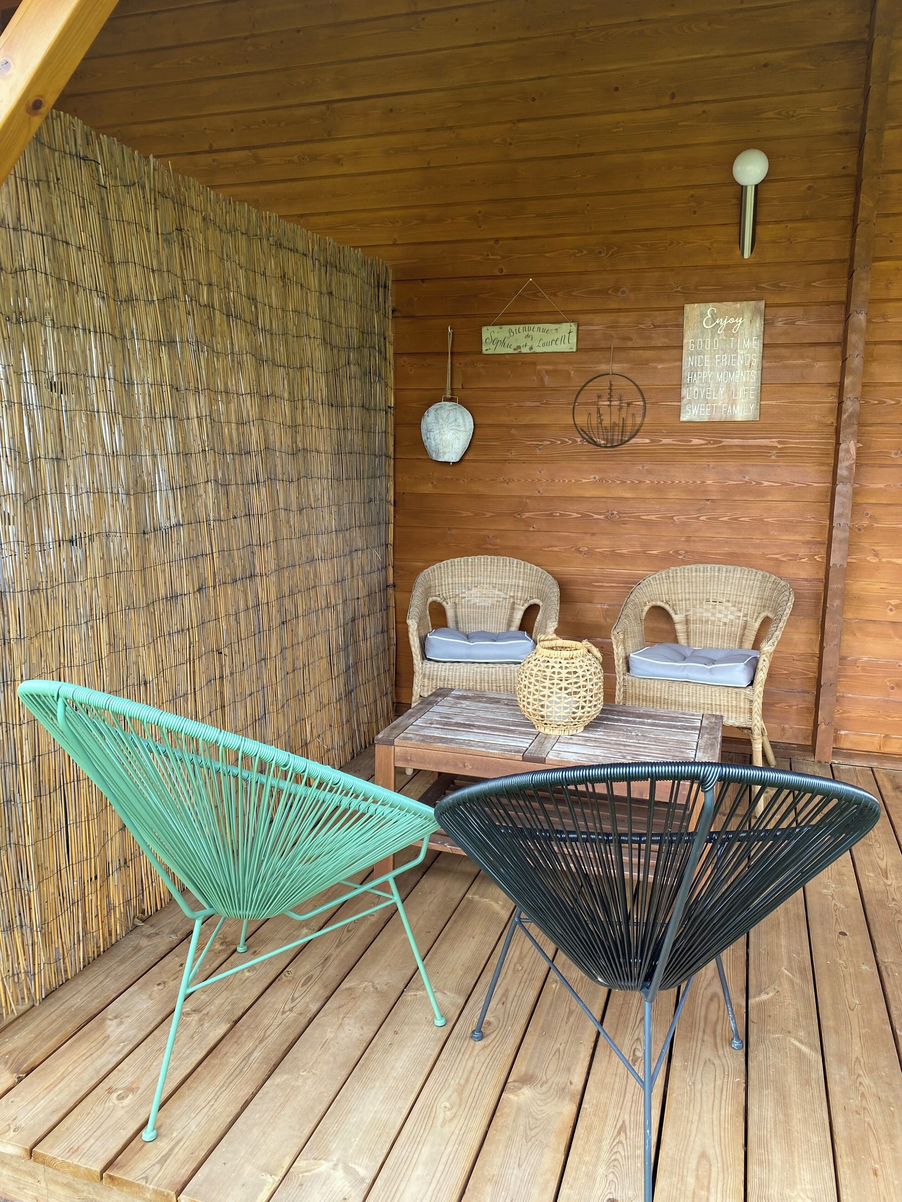 Una terraza de madera con sillas de mimbre y una mesa.