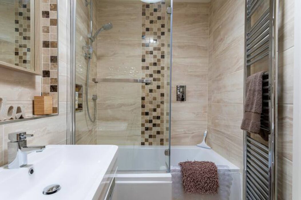 Een moderne badkamer met een douche met glazen wand, een wit wastafelmeubel en een handdoekrek.