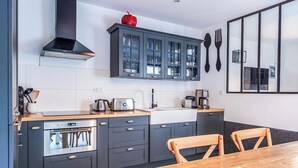 A modern kitchen with grey cabinets, a wooden table, and a red apple on the counter. - Architect-designed house in Tours center garden terrace, A/C, parking (Tours)