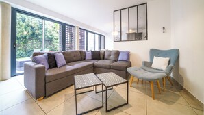 A modern living room with a sectional sofa, two square coffee tables, a blue armchair, and a large mirror on the wall. - Architect-designed house in Tours center garden terrace, A/C, parking (Tours)