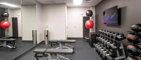 A gym with exercise equipment, a television, and a mirror.