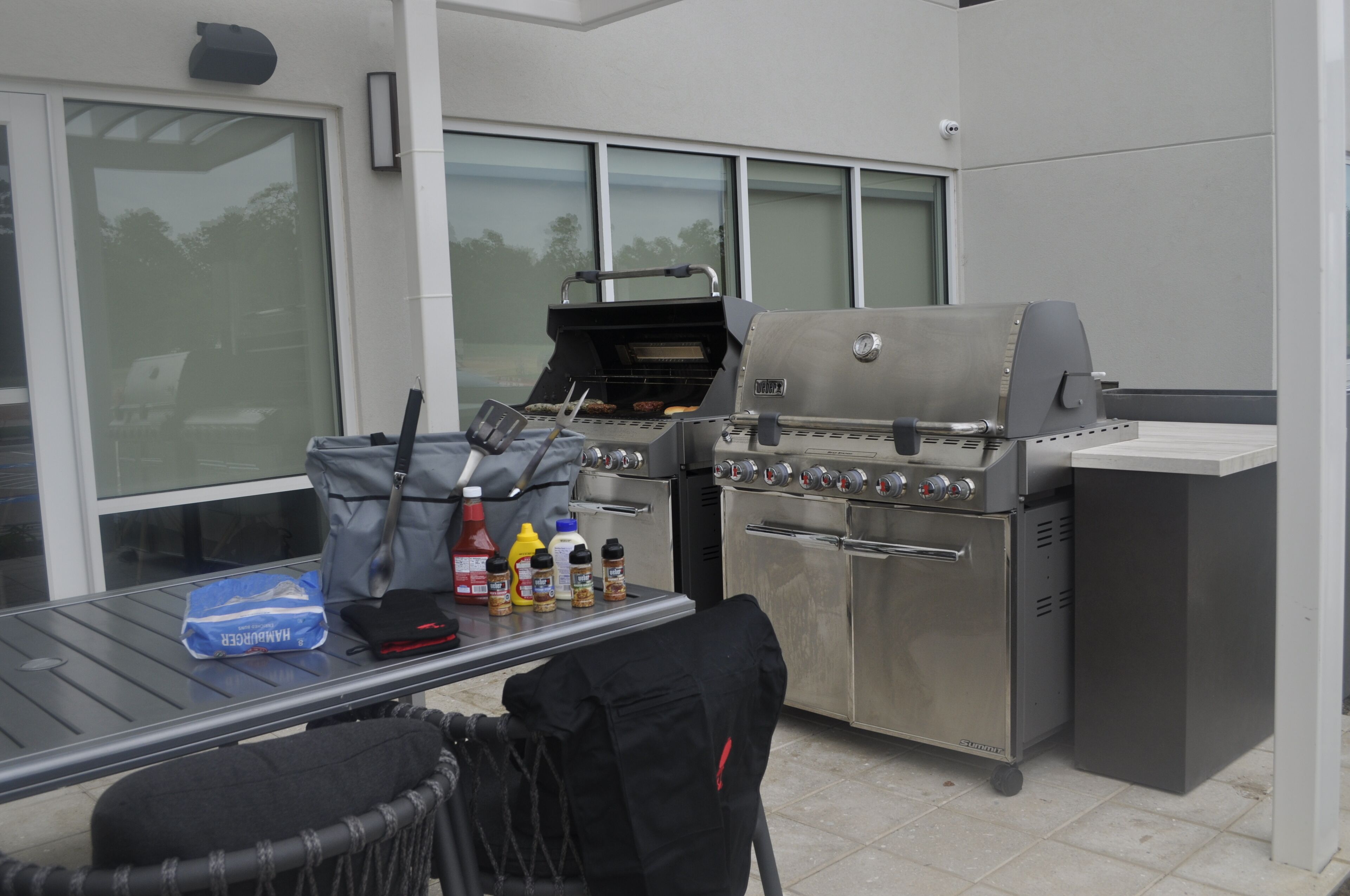 Un espace cuisine extérieur comprenant un barbecue et une table avec des condiments.