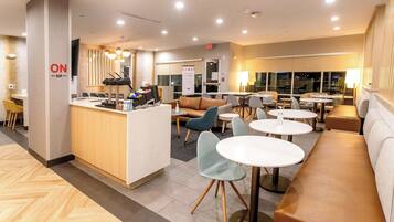 A modern hotel lobby with a reception desk, seating areas, and large windows.
