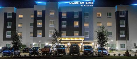A hotel with multiple floors, a parking lot with several cars, and a sign indicating it is a TownePlace Suites by Marriott.