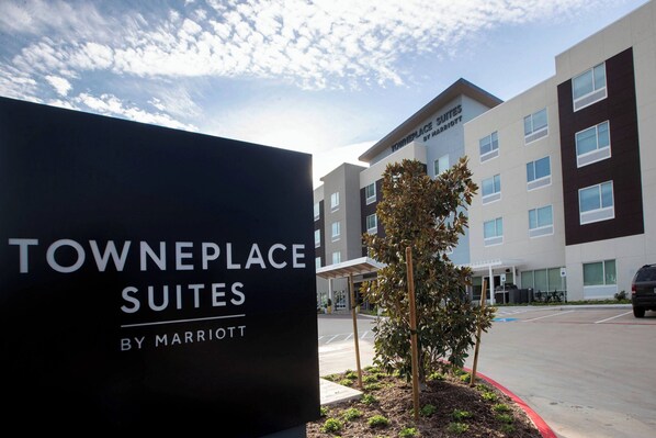 A sign for Towneplace Suites by Marriott with a modern building in the background.