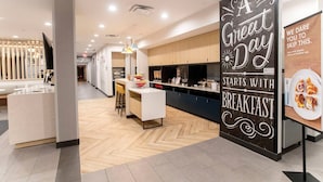A modern hotel lobby with a reception desk, a central seating area, and a kitchen counter. - TownePlace Suites by Marriott Conroe (Conroe)