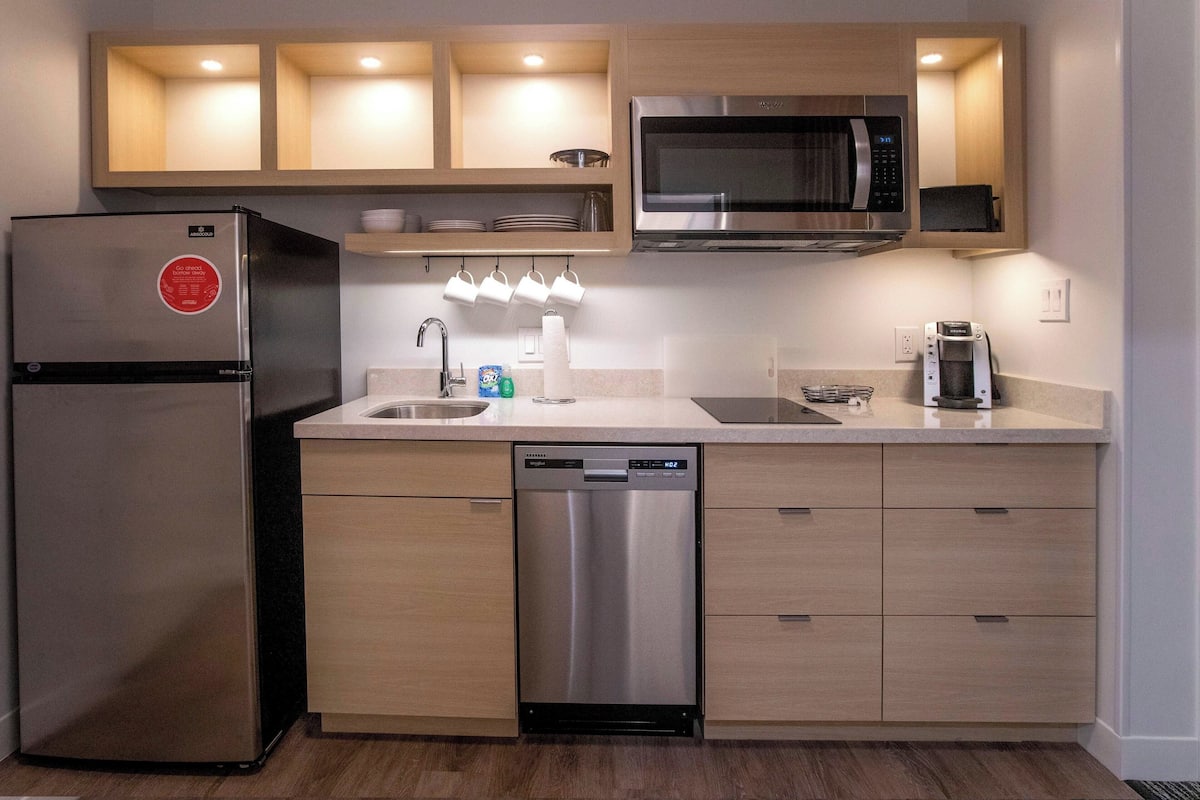 A modern kitchen with stainless steel appliances, wooden cabinets, and a dishwasher.