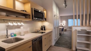 A modern kitchen with a dishwasher, microwave, and coffee maker. There are wooden cabinets and a countertop. - TownePlace Suites by Marriott Conroe (Conroe)