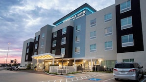 A multi-story hotel with a modern design, featuring a prominent entrance with a covered walkway and a parking area with marked spaces. - TownePlace Suites by Marriott Conroe (Conroe)