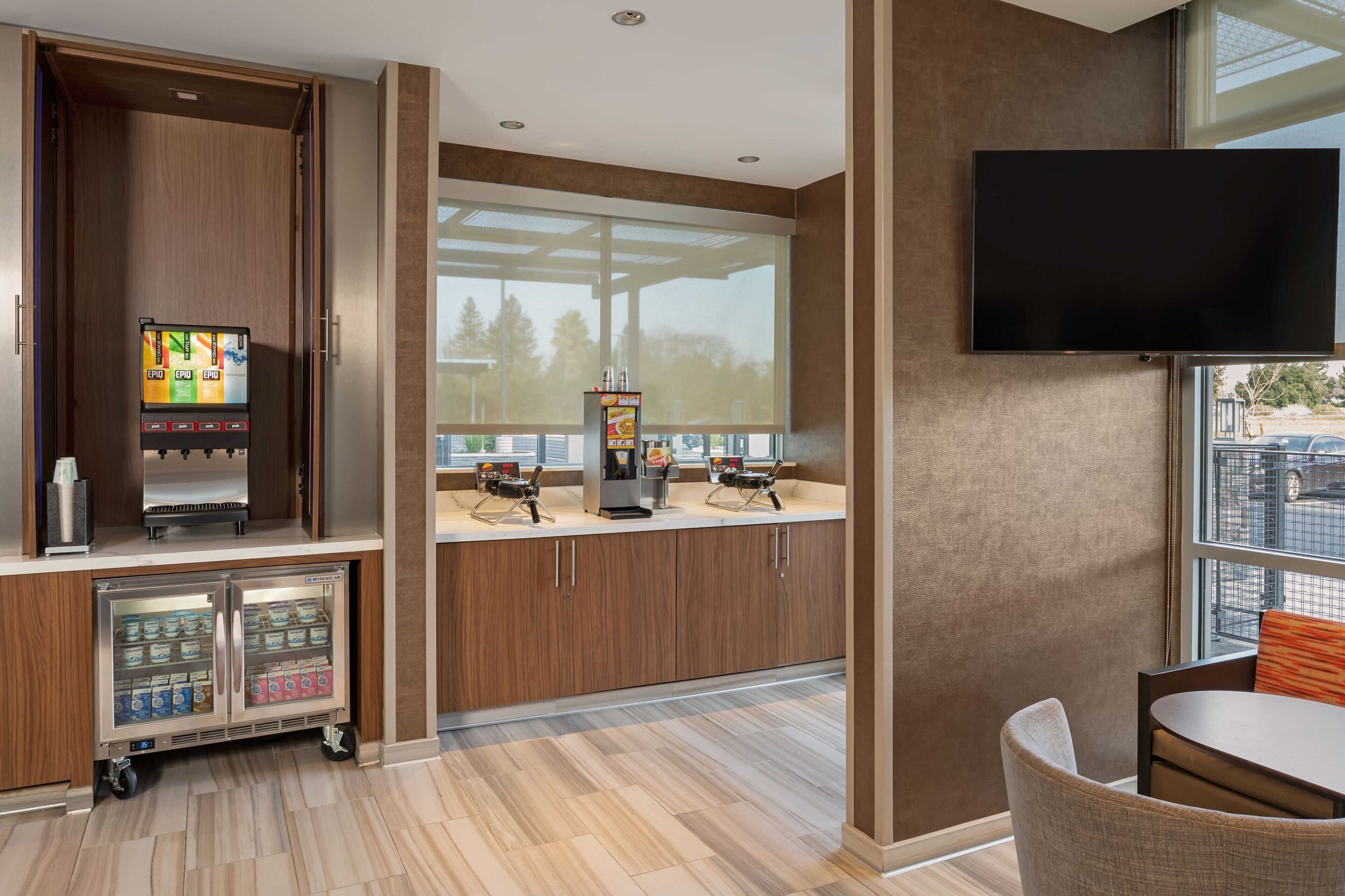 Une chambre d’hôtel moderne équipée d’un minibar, d’une machine à café, d’une télévision et offrant une vue sur l’extérieur.