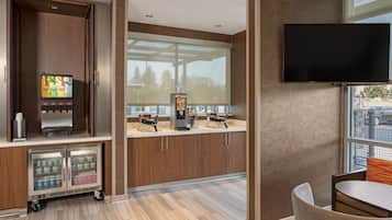 Une chambre d’hôtel moderne équipée d’un minibar, d’une machine à café, d’une télévision et offrant une vue sur l’extérieur.