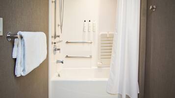 A modern bathroom with a bathtub, a towel rack, a handrail, and a shower curtain.