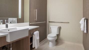 Un baño moderno con lavamanos, espejo e inodoro.