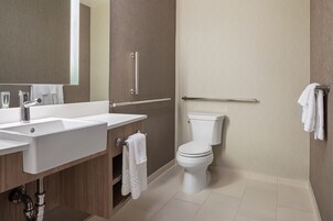 Un baño moderno con lavamanos, espejo e inodoro.
