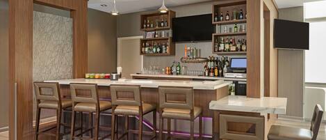 A modern kitchen with a bar area, wooden cabinets, and a flat-screen TV.