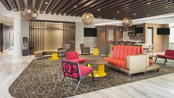 A modern lobby with a bar area, seating arrangements, and an ATM.