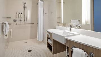 A modern bathroom with a shower, two sinks, a large mirror, and a wooden vanity.