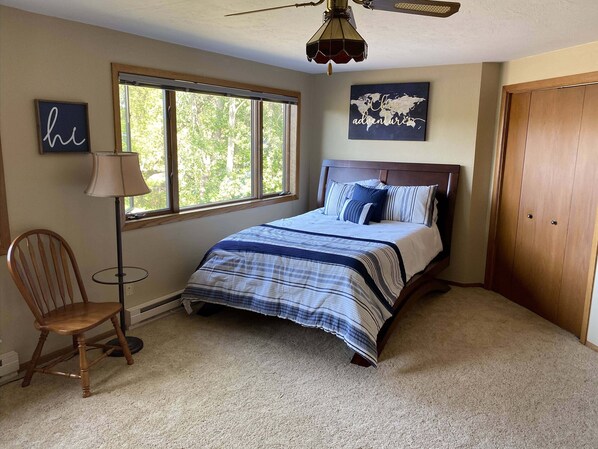 A bedroom with a bed, a chair, a lamp, a window, and a wardrobe. - House on the Harbor Waterfront Home (Sturgeon Bay)