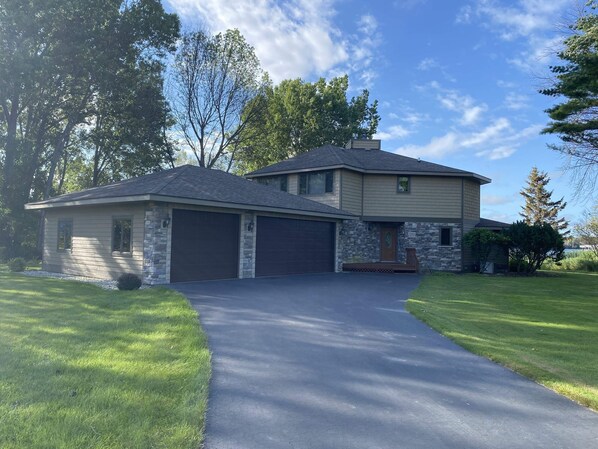 A two-story house with a stone facade, a garage, and a well-maintained lawn. - House on the Harbor Waterfront Home (Sturgeon Bay)